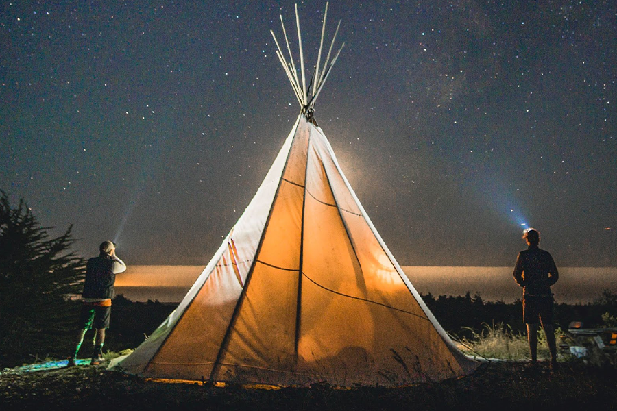 Two people standing beside tent during the night