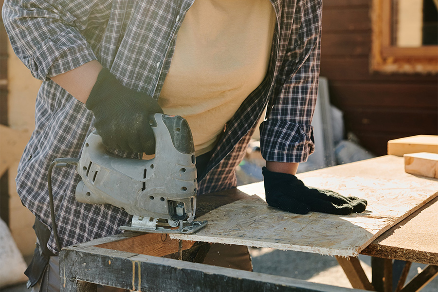 Woman in gloves using a jigsaw to make curves