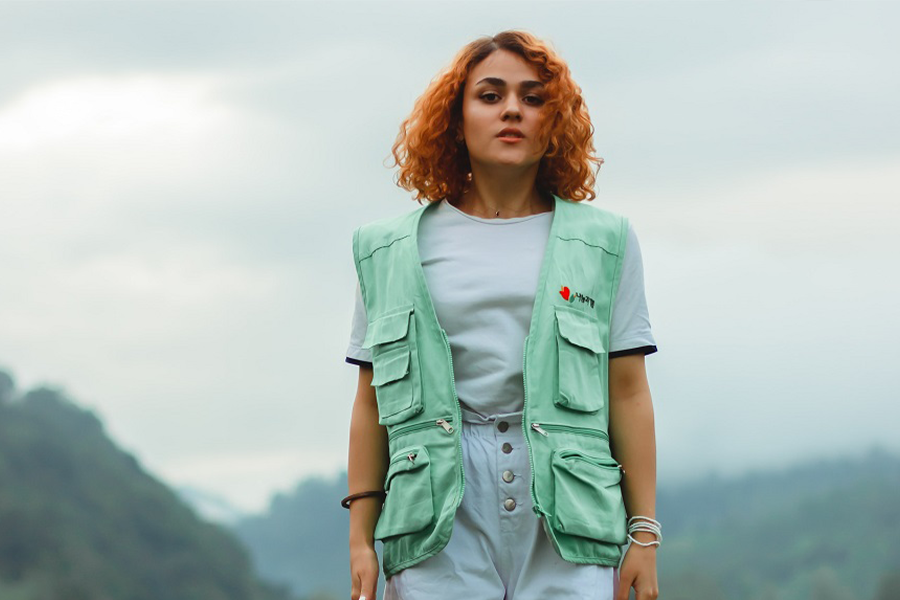 Woman in a light green fishing vest jumping