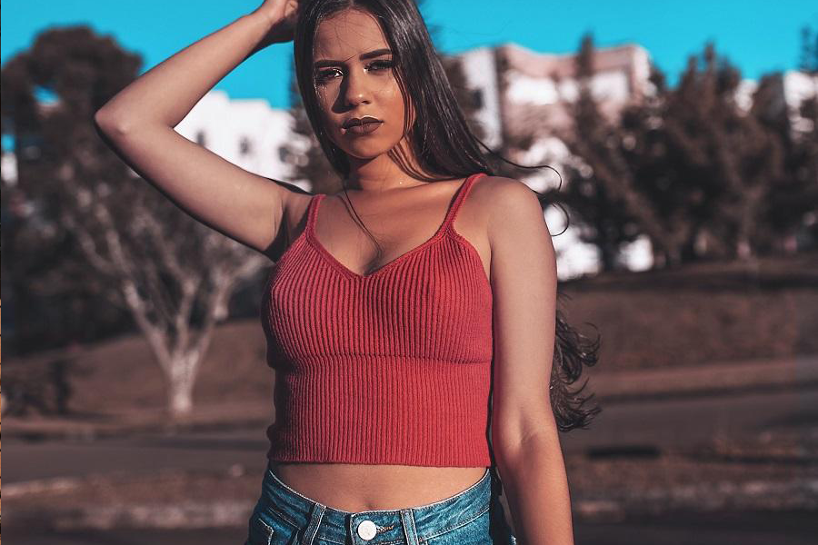 A woman in a red tank top over a denim