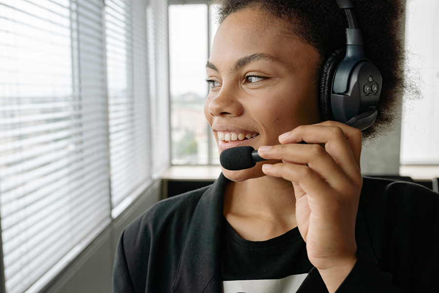 Smiling lady using gaming headset's microphone to communicate