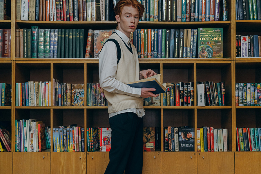 Student in shirt, knitted vest, and black pants