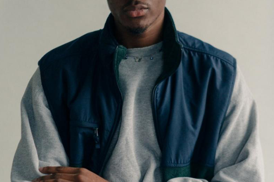 Man wearing gray sweater with blue and green vest