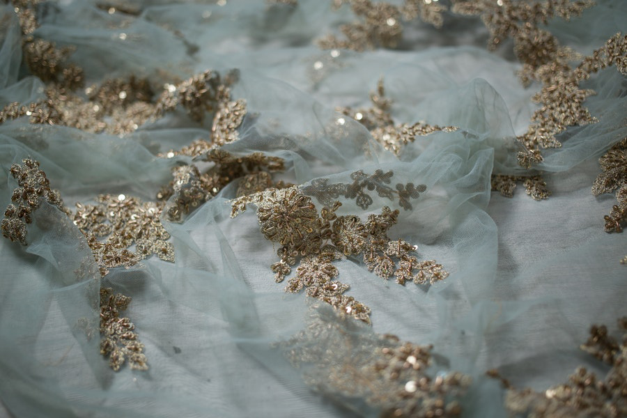 A white sheer fabric with brown lace appliques