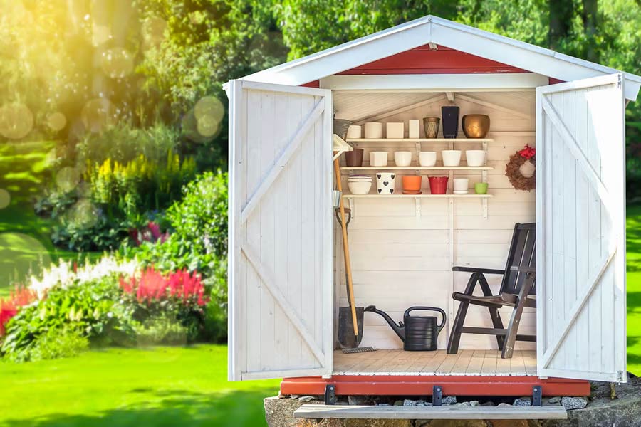 Garden shed filled with gardening tools and green sunny garden