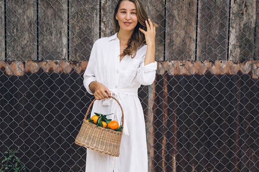 Woman in cream-colored shirt dress holding a basket