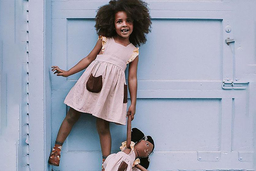 A girl in a pink dress with a doll