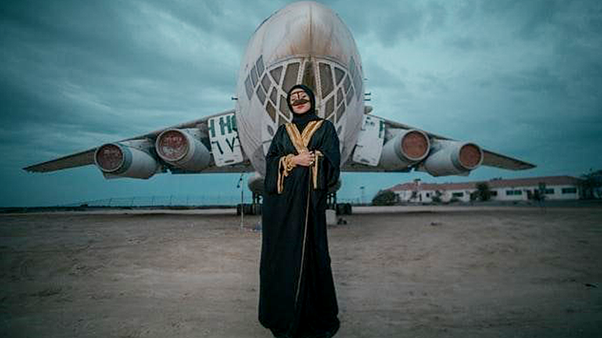 A Woman Wearing A Black Abaya In Front Of A Plane