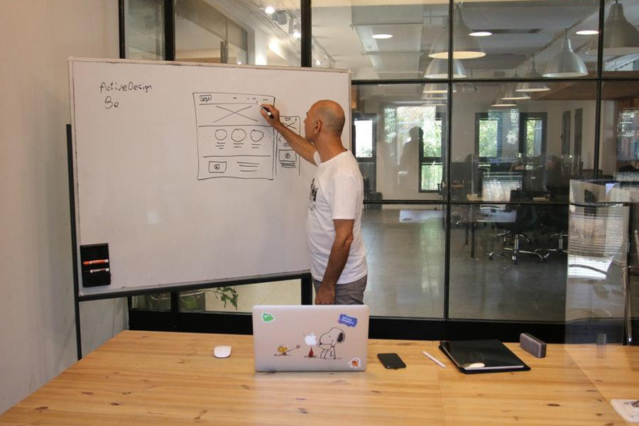 Man in a white printed t-shirt writing on a whiteboard