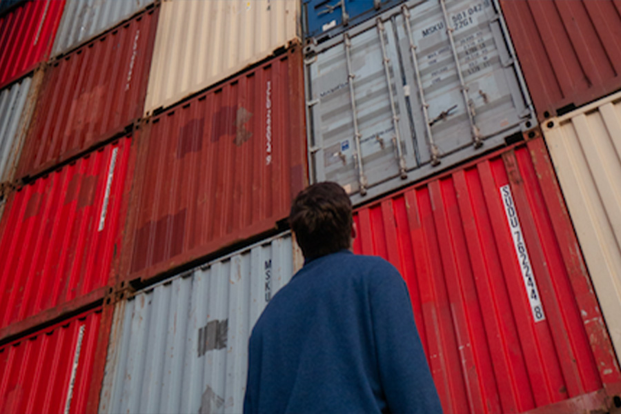 Man looking at the choices of stacked freight containers