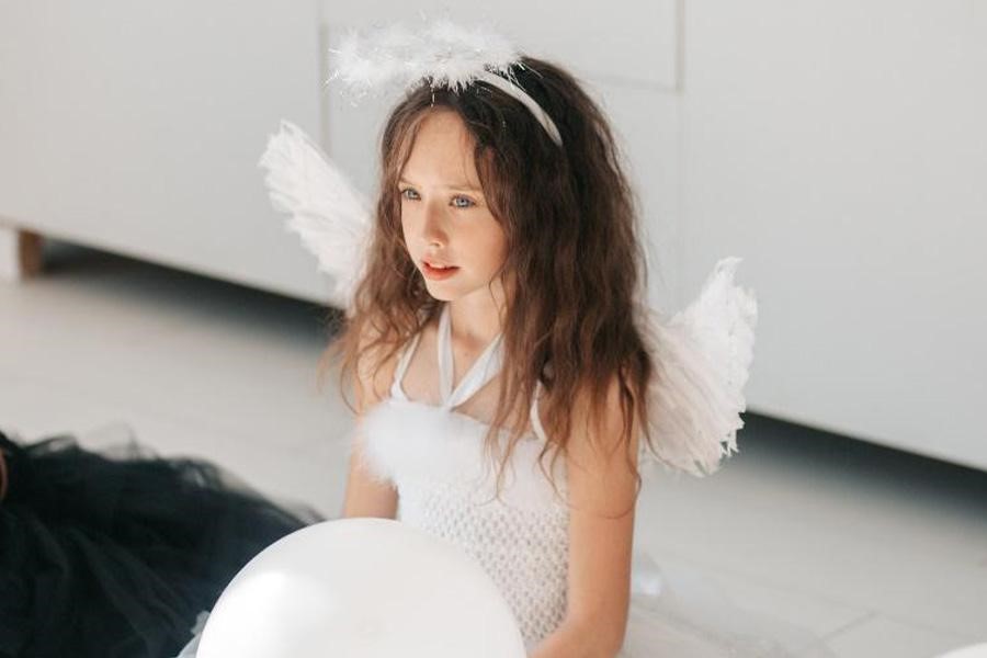 Young girl dressed in white angel costume