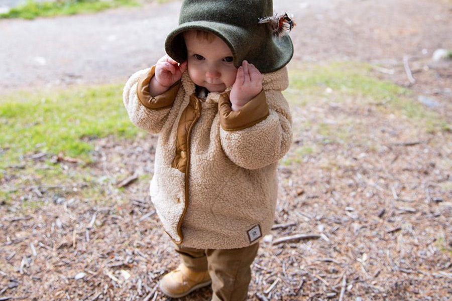 Baby rocking a beige fleece jacket and green hat