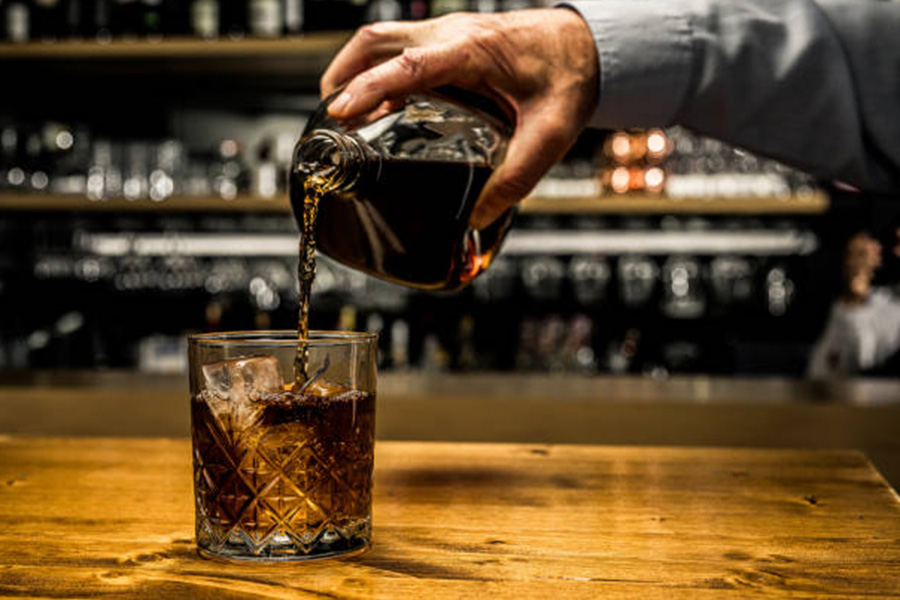 Classic whisky glass with whisky being poured inside