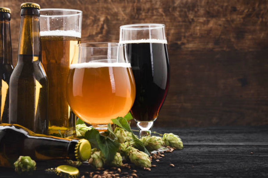 Different styles of beer glasses filled with beer on table