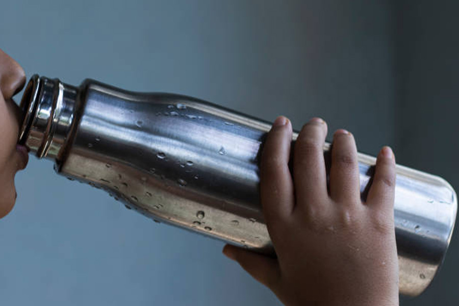 A large stainless steel water bottle being drunk from