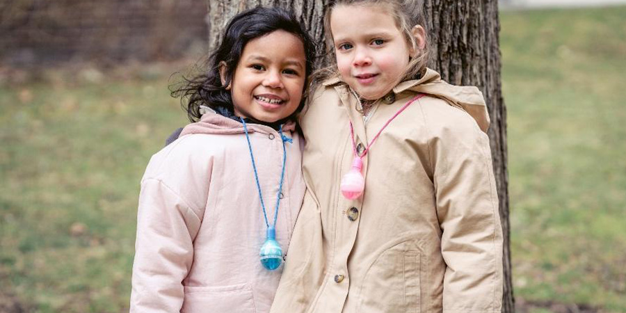 Two smiling girls wearing bright-colored puffer jackets