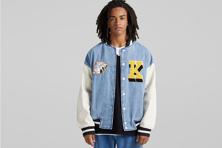 Young guy with dreadlocks wearing a denim varsity jacket