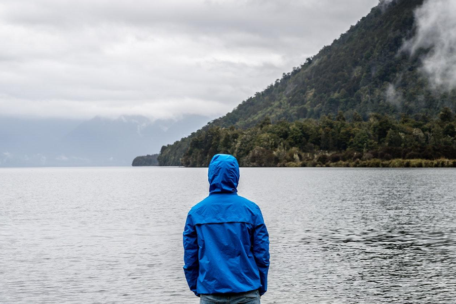 Un homme dans un sweat à capuche regardant dans la mer