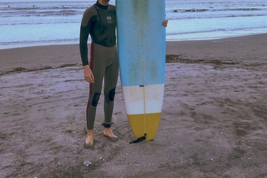 Un homme portant une combinaison grise tenant une planche de surf