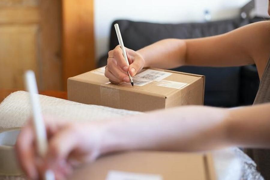 A person writing on brown cardboard boxes