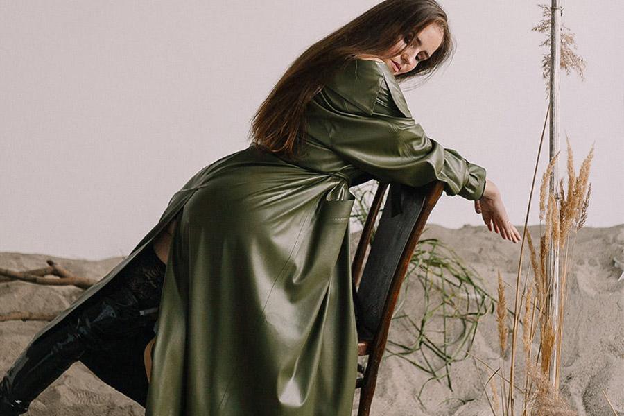 Dame portant un trench-coat en cuir vert armée