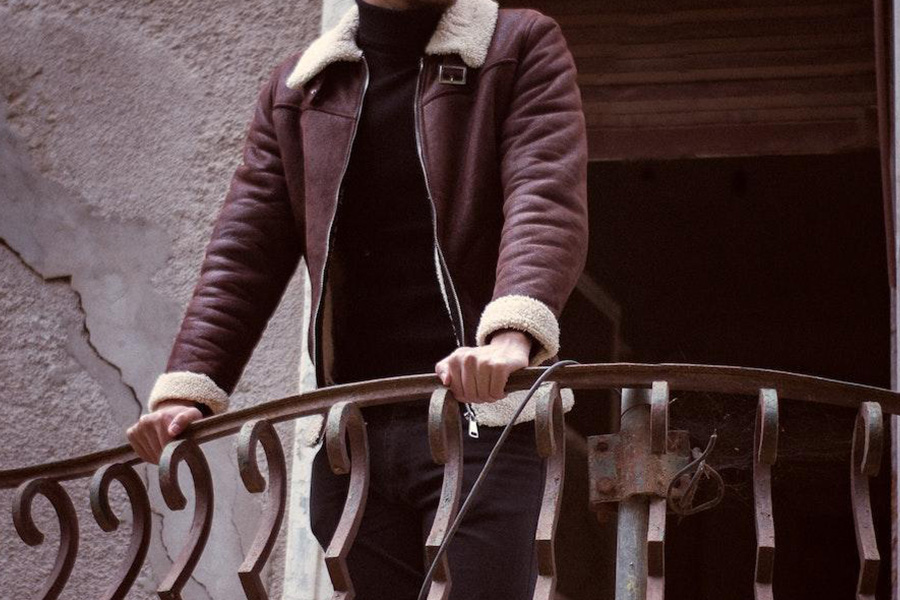 Man on a balcony with burgundy bomber jacket