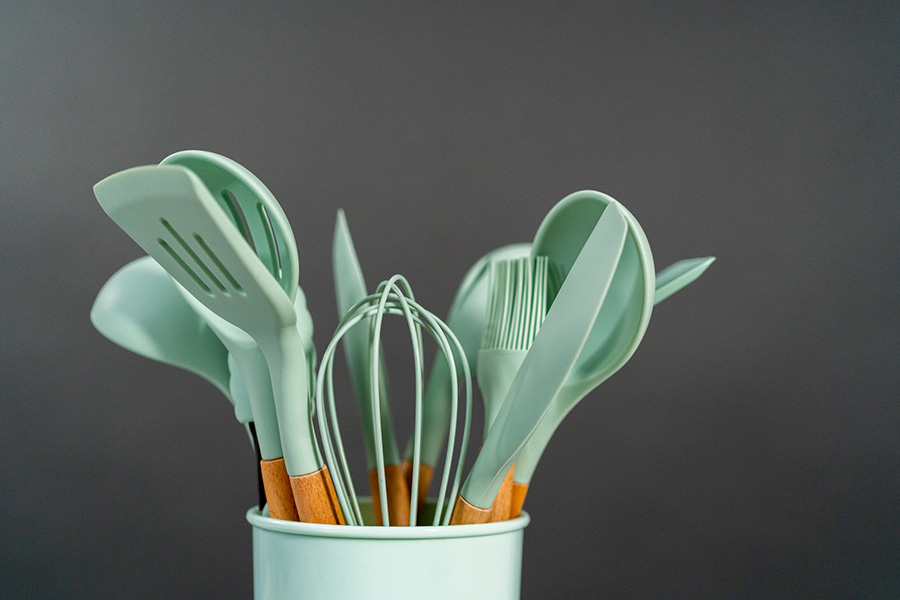 Utensílios de cozinha de silicone com alças de madeira em fundo preto