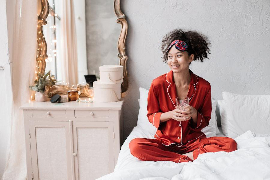 Woman rocking a red pajamas set on a bed