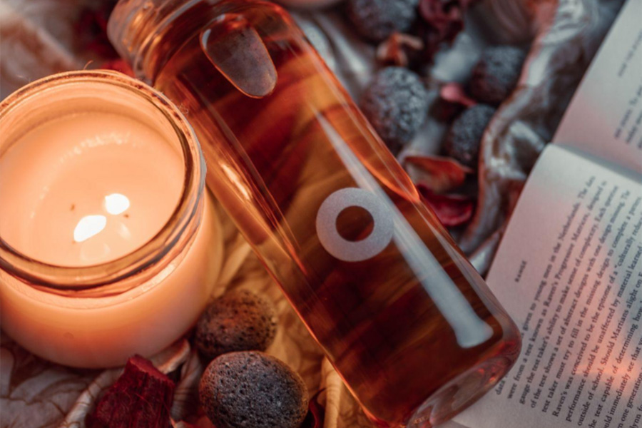 A candle placed next to a cup and waterbottle