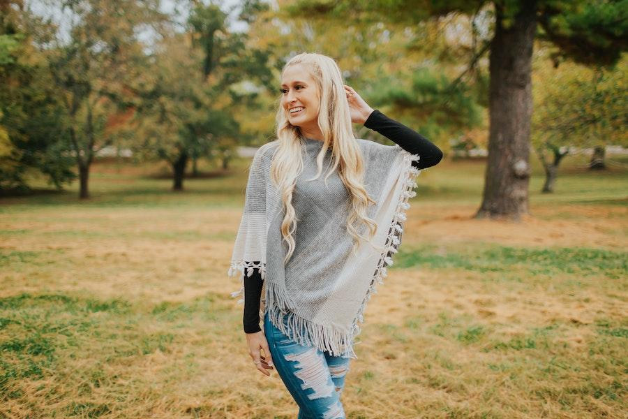 Una señora rubia sonriente meciendo un poncho gris