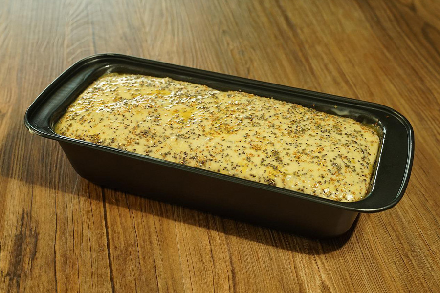 Bread dough in a black loaf pan