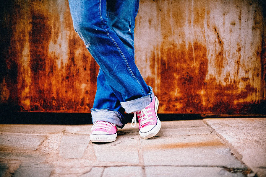 Foto jarak dekat wanita menyilangkan kaki dengan jeans tukang kayu yang santai