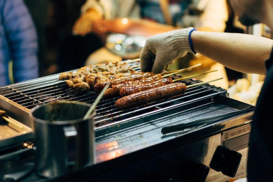 Man grilling sausages on a gas grill