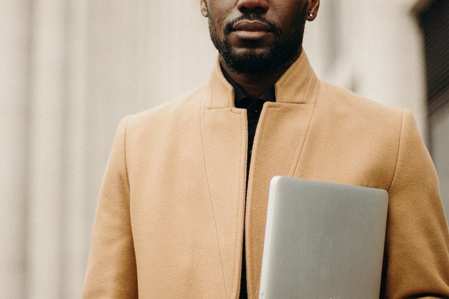 Man holding white object with light brown blazer