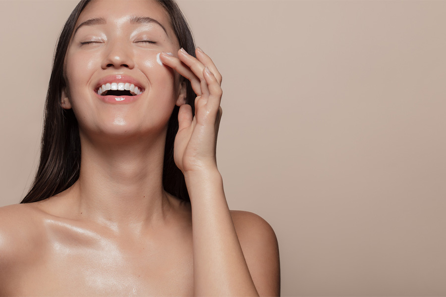 Smiling woman applying skin cream