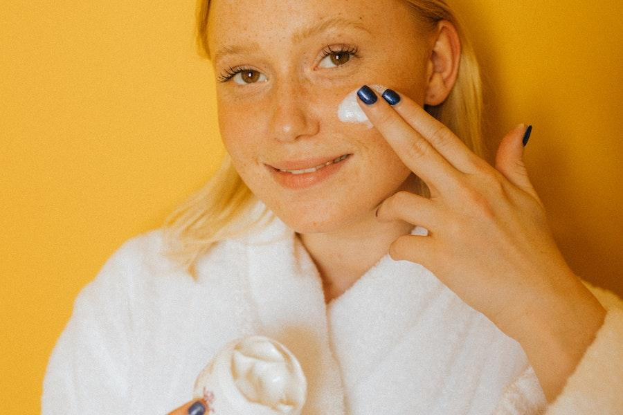 Teenager smiling while applying skincare product