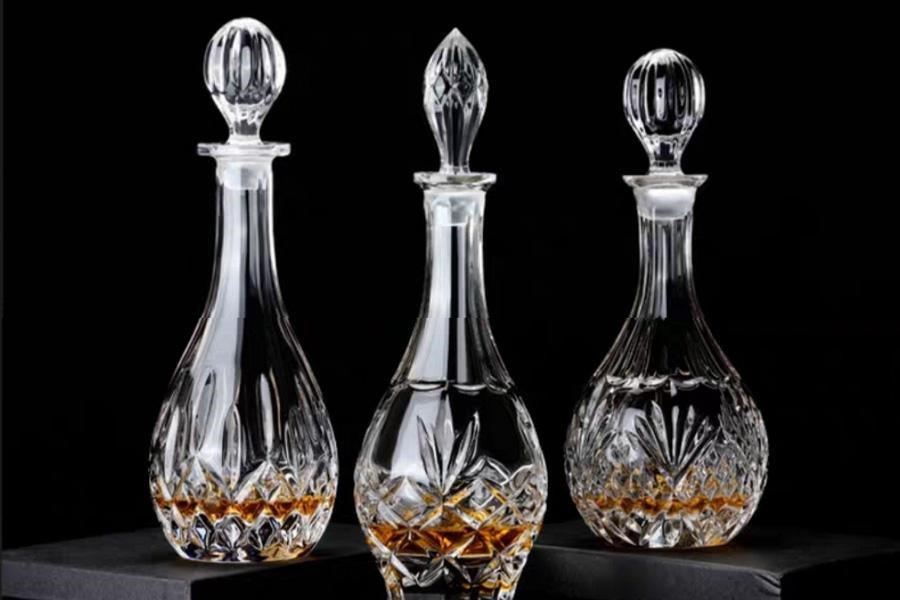 Three premium glass alcohol bottles with decorative lids