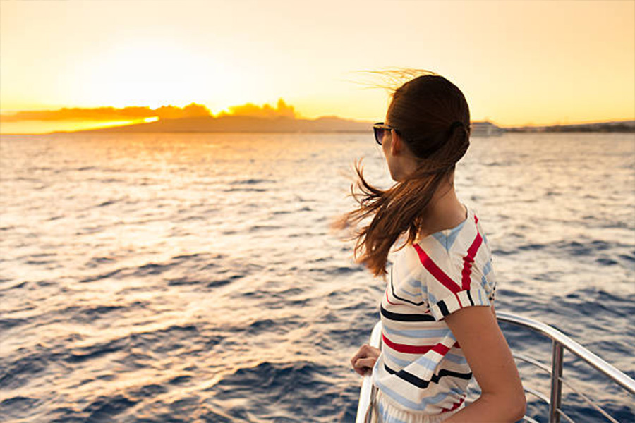 Donna che indossa una maglietta a righe al tramonto in barca