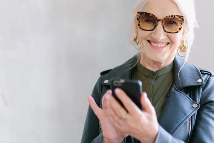 Alegre mulher na menopausa usando smartphone em óculos da moda