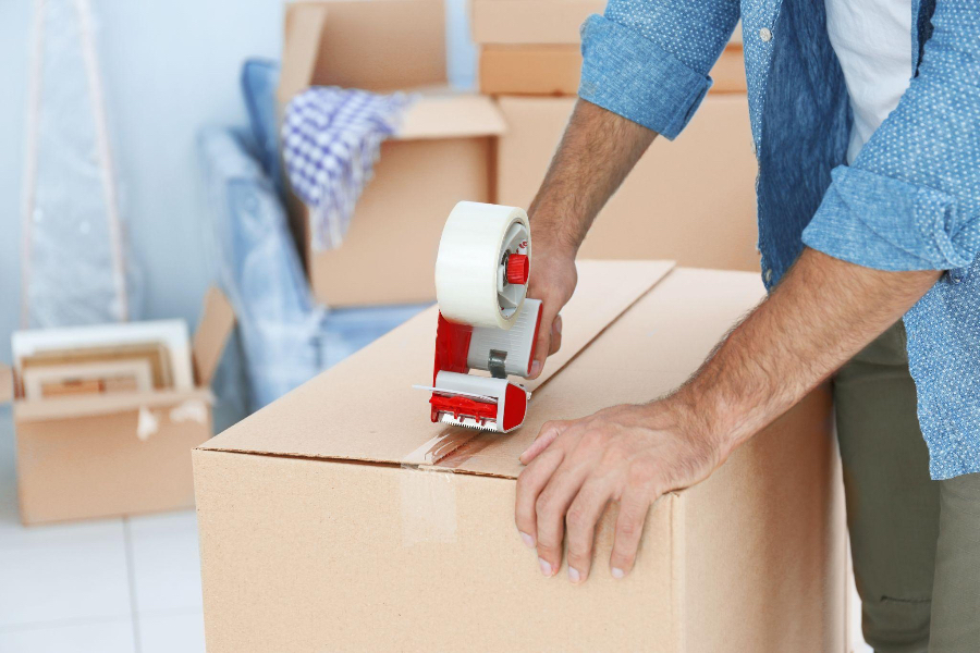 Man packing cardboard box with tape