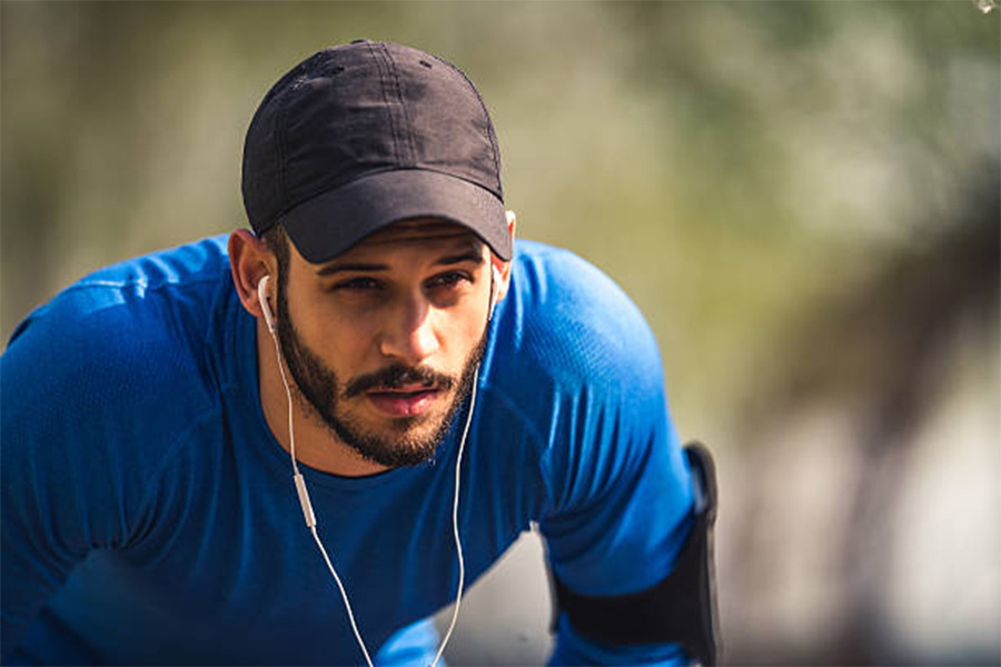 Homem fazendo uma pausa na corrida usando chapéu de corrida preto