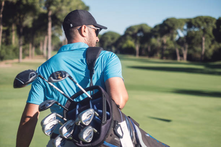 Homem andando no campo de golfe usando um chapéu de golfe