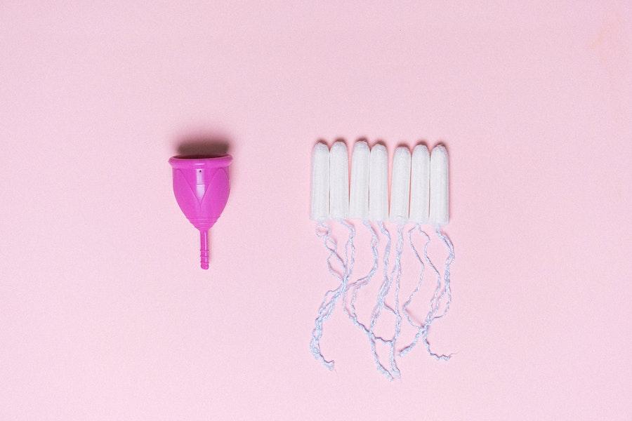 Copos de menstruação e tampões em um fundo rosa