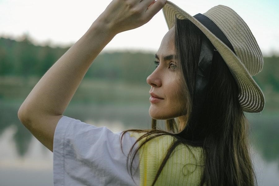 Woman holding a straw hat looking sidewaysWoman holding a straw hat looking sideways