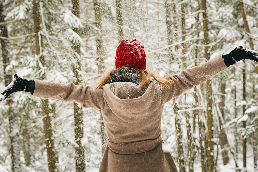 Woman in a snowy forest wearing a red knitted hat