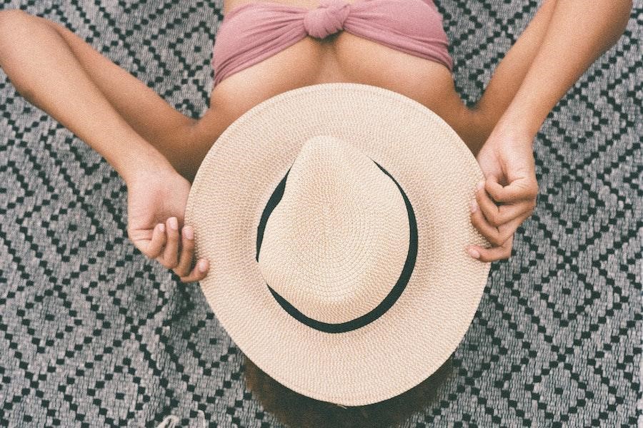 Woman lying down while holding a straw hat