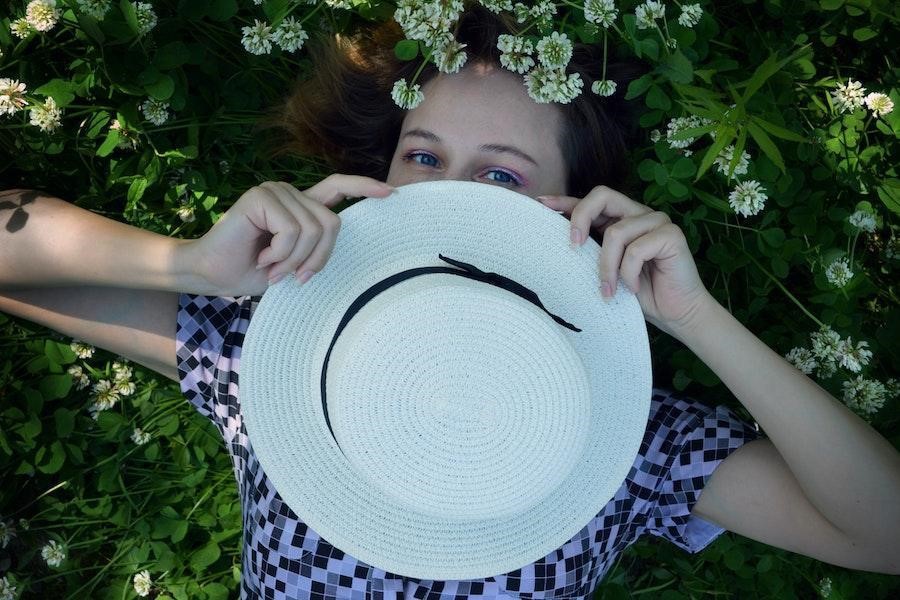 Woman lying down while holding a white straw hat