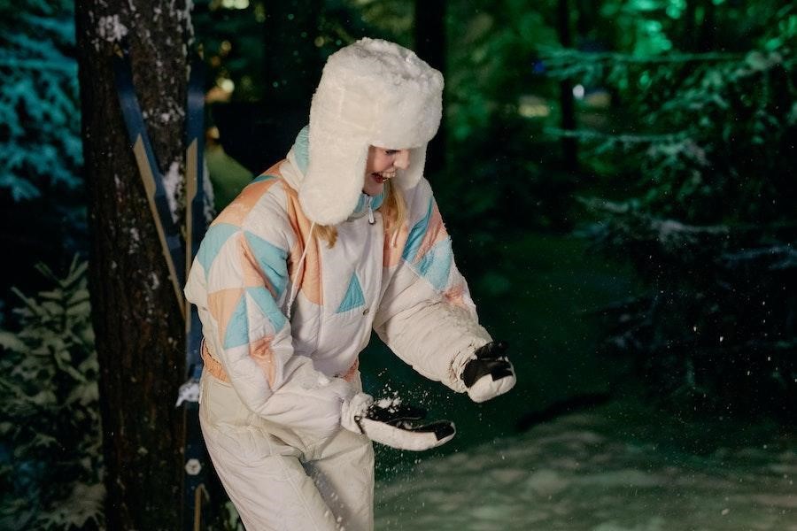 Mulher brincando com neve em um chapéu ushanka branco