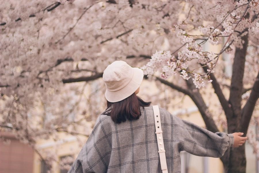 Woman under a tree wearing a white bucket hat