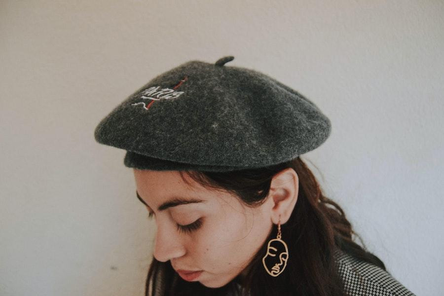 Femme portant un béret gris et regardant vers le bas